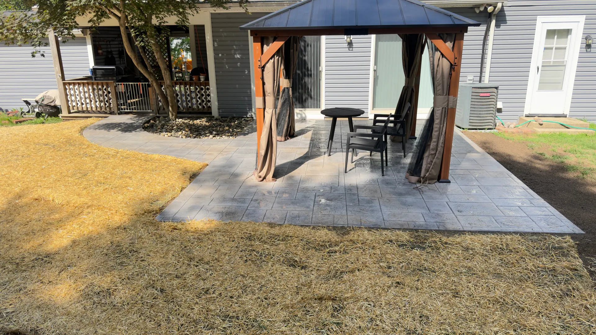 A finished stamped concrete patio with a gazebo and seating